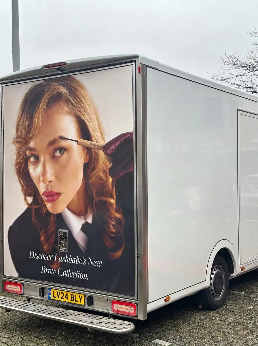 Rear panel of a white van carrying a beauty brand advert with a UK number plate